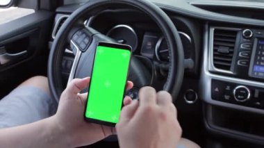 Arabanın içinde boş yeşil ekran olan kromakey cep telefonu. Model dokunmatik ekran. Yeşil akıllı telefon görüntüsü.