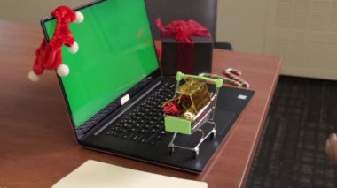 Genç bayanların alışveriş arabalarını alıp yeşil ekran ve arka planda Noel süslemeleri olan küçük hediyelerle dolu yakın plan fotoğrafları. Teslimat konsepti. Yapılandırma içeriği