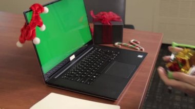 Genç bayanların el arabalarını küçük hediyelerle doldurup yeşil ekranlı klavyeye yerleştirmeleri ve arka planda Noel süslemeleri. Teslimat konsepti. Yapılandırma içeriği