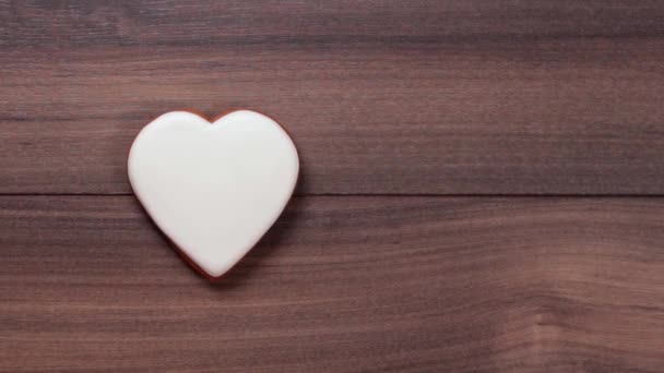 Mano femenina colocar una galleta blanca corazón grande y otra mano colocar segundo corazón blanco sobre fondo de madera. Concepto de amor. Sitio de citas. Problemas de confianza. Espacio para texto. — Vídeos de Stock