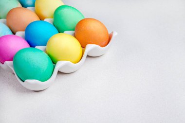 Beyaz masada duran parlak renkli Paskalya yumurtaları. Geleneksel dekorasyon