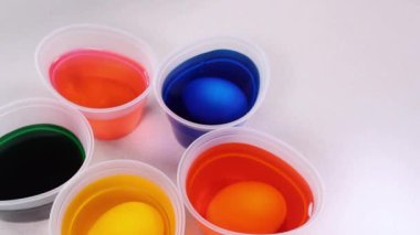 Yumurta süslemesi için boyalı parlak renkli gözlükler. Beyaz bir masada renkli yumurta süsleme boyası..