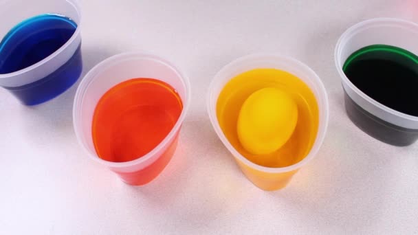 Nahaufnahme von Kinderhänden, die Ostereier mit Eierfarbe einfärben. Bunte bunte Gläser mit Farbe zum Dekorieren von Eiern. — Stockvideo