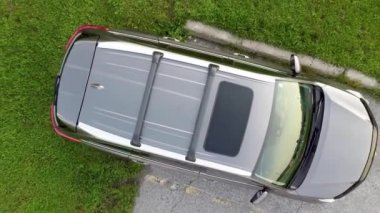 Yukarıdan aşağıya hava manzaralı İHA görüntüsü Ormanın yanındaki yeşil parka park etmiş gri arabanın üstünde uçuyor