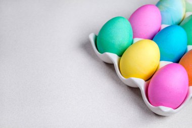 Pastel Paskalya yumurtaları beyaz masada yatıyor. Geleneksel dekorasyon