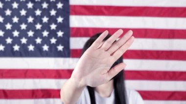 Ciddi kız avucunu kameraya uzatıp arka planda kürtaj Amerikan bayrağını durdurun diyor. Kapatın. Aile içi şiddet, ırkçılık ayrımcılığı. Kadın hakları için mücadele, sosyal sorunlar