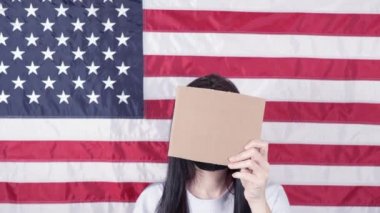Siyah maskeli genç bir kadın arka planda Amerikan bayrağına karşı 