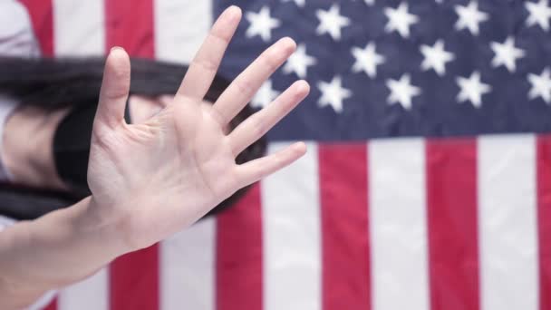 若い女性は彼女の手のひらをカメラに伸ばすの背景に中絶アメリカ国旗を停止し 閉じると言います 反家庭内暴力人種差別 女性の権利のための闘争 社会問題 — ストック動画