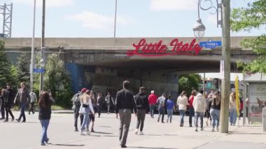 Güneşli bir sokakta yürüyen insanlar yazın tadını çıkarıyorlar. Yavaş çekim videosu. Kalabalık Küçük İtalya 'yı festival haftasında ziyaret etti. Ottawa, On, Kanada - 18 Haziran 2022