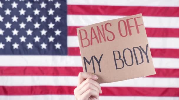 看板を持っている女性は背景に私の体アメリカの旗を禁止します 中絶法の厳格化に対する抗議 全国の女性がストライキを行う Covid 19に対する保護フェイスマスクを着用 — ストック動画