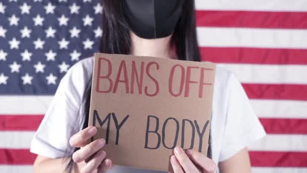 Γυναίκα Κρατώντας Μια Πινακίδα Bans Body Αμερικανική Σημαία Στο Παρασκήνιο — Αρχείο Βίντεο