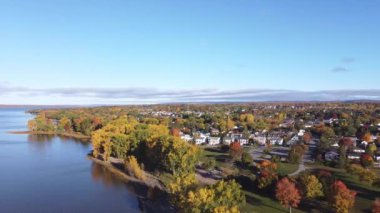 Birds eye view of beautiful autumn city landscape, with dense colorful trees, the camera slowly spinning rising. Aerial footage of a town showing typical suburban housing estates with rows of houses.
