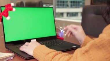 Virtual Christmas Family video call remote conference Computer green screen view. Woman show gift on camera working from home office. Happy hour party online. Ottawa, ON Canada July 24, 2022.