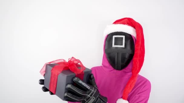 Squid Игры Розовый Охранник Рождественской Шляпой Показывает Подарочную Коробку Белом — стоковое видео