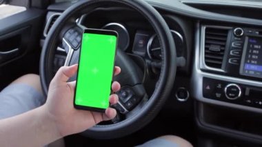 Modern arabalarda boş yeşil ekranlı kromakey cep telefonu kullanan bir adam. Model dokunmatik ekran. Akıllı telefon görüntüsü kaydırılıyor