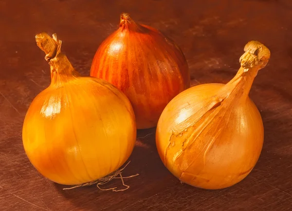 Three onions on a wooden board — Stock Photo, Image