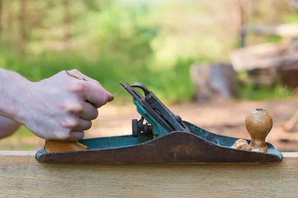 Handen van een timmerman geschaafd hout. — Stockfoto