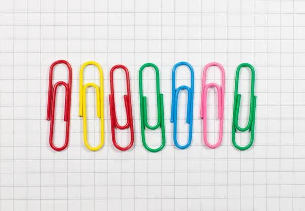 Pinzas de papel coloridas en una hoja blanca de papel en la jaula — Foto de Stock