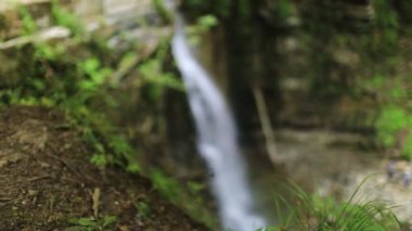 Şelale arka planında bulanık ya da bokeh etkisi. Taş uçurum ve arka planda düşen akıntı bulanık.