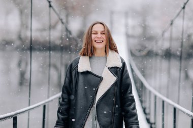 Bir kadın kış günü asma köprüde nehrin üzerinde yürüyor. Soğuk karlı bir günde, kalın elbiseli genç bir kız tahta bir yaya köprüsünde duruyor..