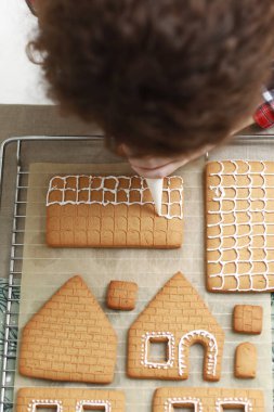 Eller Noel kurabiyelerini mum ve süs eşyasıyla süslüyor. Kapatın. Dondurmalı zencefilli ev yapıyorum. Tatil hazırlığı ve gelenek.