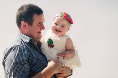 Baba, güneşli bir günde göl kenarında küçük kızına sarılıyor. Yaz tatili kavramı. Babalar günü, bebekler günü. Aile doğada birlikte vakit geçiriyor. Aile görünüşü. seçici odak.