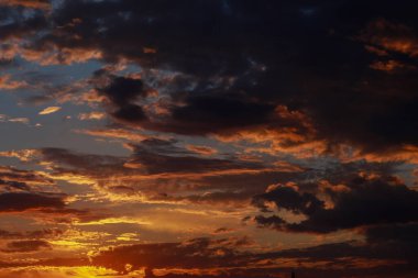 Turuncu gökyüzünde kara astarlı ve bulutlu güneşin doğuşunun ya da batışının muhteşem manzarası. Canlı ve renkli bir arkaplan.