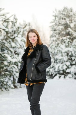 Kısa saçlı, karlı ormanda karlı gömlekli genç ve güzel bir kadın. kış tatili.