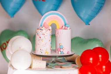 Gökkuşaklı büyük doğum günü pastası, renkli serpintiler. Bir çok renkli kalp balonunun arka planında. doğum günü partisi.