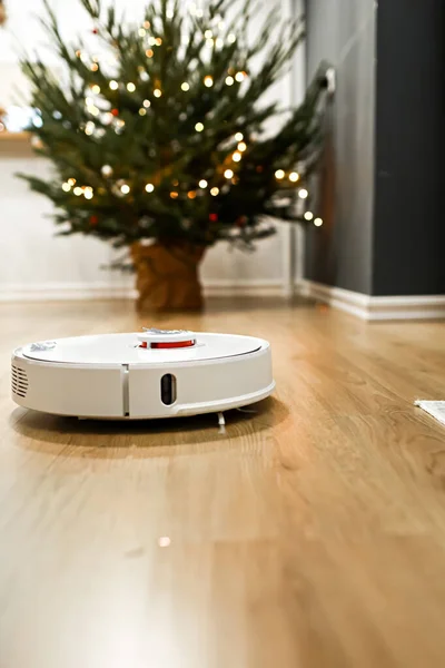 スマートホーム ロボット掃除機は自動洗浄を行います 新年の後にクリスマスツリーの針からパケットをきれいにします クリスマスツリーの近くで休暇後に掃除する — ストック写真
