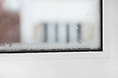 Camda su buharı olan plastik bir pencere. Çift camlı PVC pencere. Konsept: yoğunluk, sıcaklık farkı, soğutma ve nemli kusurlu plastik pencere
