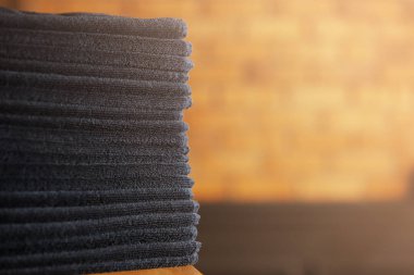 Tahta bir masaya siyah banyo havluları ve tuğla duvar arkaplanı. Spa salonu, berber dükkanı..