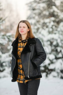 Kısa saçlı, karlı ormanda karlı gömlekli genç ve güzel bir kadın. kış tatili.