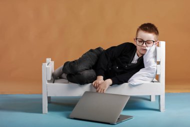 Uzaktan öğrenme çevrimiçi eğitim. Gözlüklü öğrenci yatağında uyuyor. Çocuk evde çalıştıktan sonra yorgun. dizüstü bilgisayarı kapat.