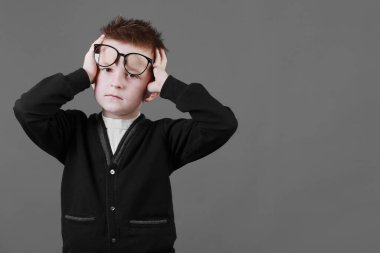 Üzgün, üzgün, gözlüklü, acı dolu bakışları olan, alnında el ele tutuşan bir öğrenci. Hüsrana uğramış hasta çocuk korkunç bir baş ağrısı yaratıyor..