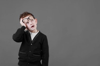 Üzgün, üzgün, gözlüklü, acı dolu bakışları olan, alnında el ele tutuşan bir öğrenci. Hüsrana uğramış hasta çocuk korkunç bir baş ağrısı yaratıyor..