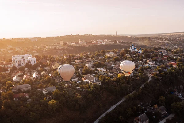 stock image Two air balloons flying over green park and small european city at summer sunrise.