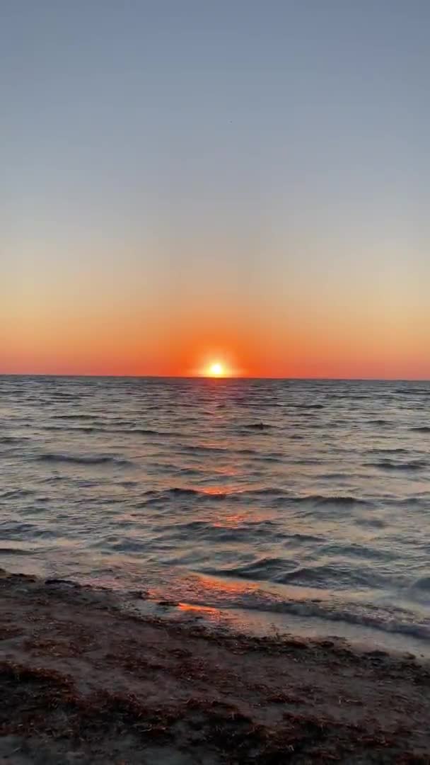 Belo nascer do sol. Céu azul alaranjado e dourado. Mar de ouro. Som de ondas o mar na praia ao nascer do sol. Pôr do sol. Pôr do sol com vista para o mar. vídeo vertical. ruído nas sombras — Vídeo de Stock