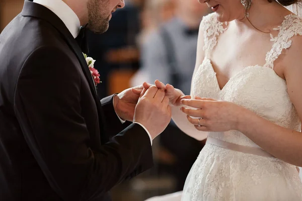 Hands of bride and groom in solemn process of exchanging rings, symbolizing the creation of new happy family. Groom putting a ring on bride\'s finger during wedding ceremony.