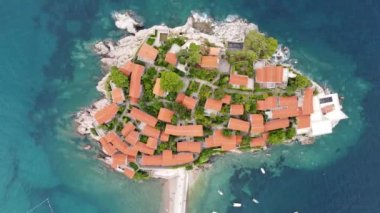 Karadağ 'ın Adriyatik kıyısındaki Sveti Stefan adasının Akdeniz üzerindeki hava aracı görüntüsü. Aziz Stephen, mavi denizin ve ünlü yaz tatillerinin ortasındaki bir adada ve oteldir..