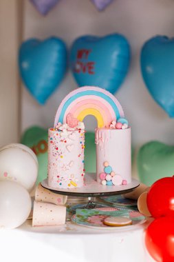 Gökkuşaklı büyük doğum günü pastası, renkli serpintiler. Bir çok renkli kalp balonunun arka planında. Doğum günü partisi. Güzel tatil.