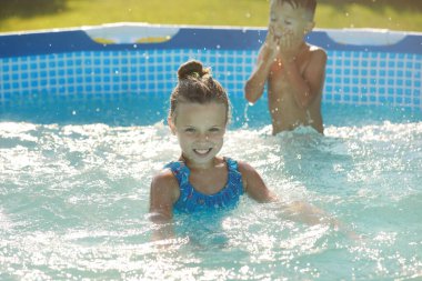 Yüzme havuzunda gülümseyen kız portresi, oynayan çocuklar. Yaz tatili ya da dersler. Havuzdaki mutlu çocuklar için yaz ve yüzme aktiviteleri.