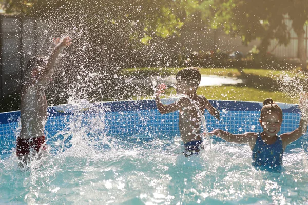 在游泳池里笑着的男孩和女孩 孩子们在飞溅和玩耍 暑假或课程 在游泳池里为快乐的孩子们安排暑期和游泳活动 — 图库照片