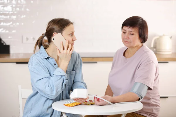 Worried Young Woman Calling Doctor Her Senior Mother Home Sick Stock Photo