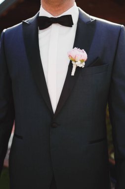 Damadın ceketinde yaka çiçeği var. Bir erkeğin ceketinde çiçek. Çiçekli ceketli bir adam.