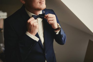 Damada kelebekli resmi bir kostüm giydir. Takım elbise, Eller, özen, kravat, düzeltme, ayarlama, moda, yay. Takım elbiseli yakışıklı bir iş adamı. Seksi bir adamın portresi.