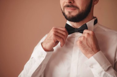 Damada kelebekli resmi bir kostüm giydir. Takım elbise, Eller, özen, kravat, düzeltme, ayarlama, moda, yay. Takım elbiseli yakışıklı bir iş adamı. Seksi bir adamın portresi.