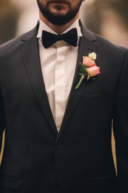 Damadın ceketinde yaka çiçeği var. Bir erkeğin ceketinde çiçek. Çiçekli ceketli bir adam.