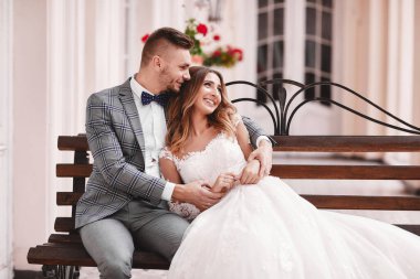 Düğün günü. Beyaz uzun elbiseli güzel gelin ve siyah takım elbiseli genç damat Avrupa 'nın tarihi şehrinde sarılıyorlar..