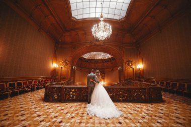 Düğün günü. Beyaz uzun elbiseli güzel gelin ve siyah takım elbiseli genç damat büyük tarihi Avrupa binasında kucaklaşıyorlar.